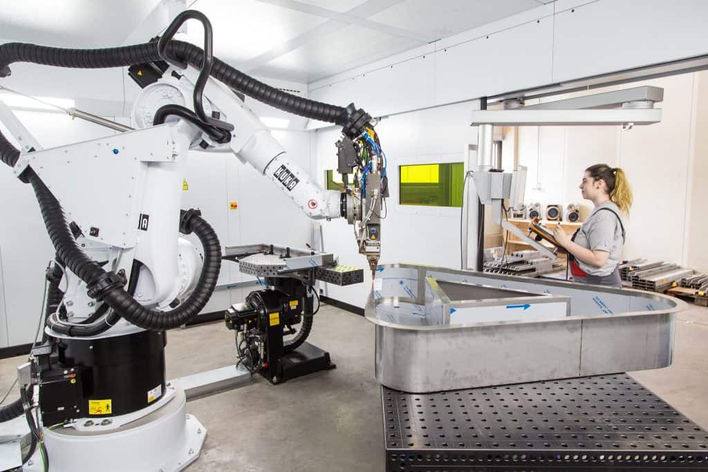 Weiblicher Lehrling führt Arbeiten mit einem Roboter aus.